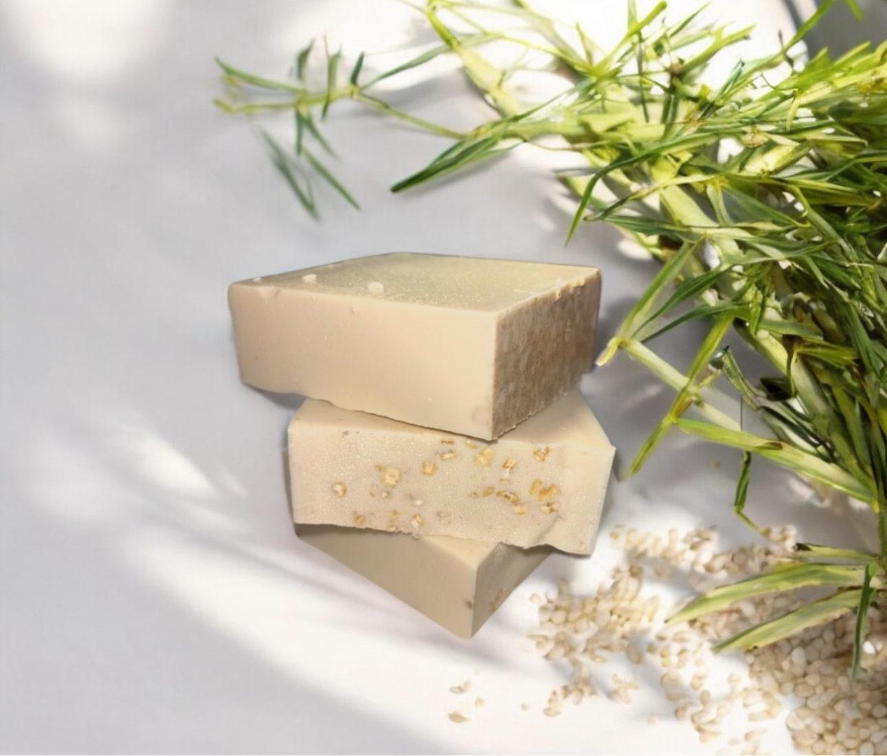 Two rectangular bars of soap with visible ingredients on a light background with greenery.