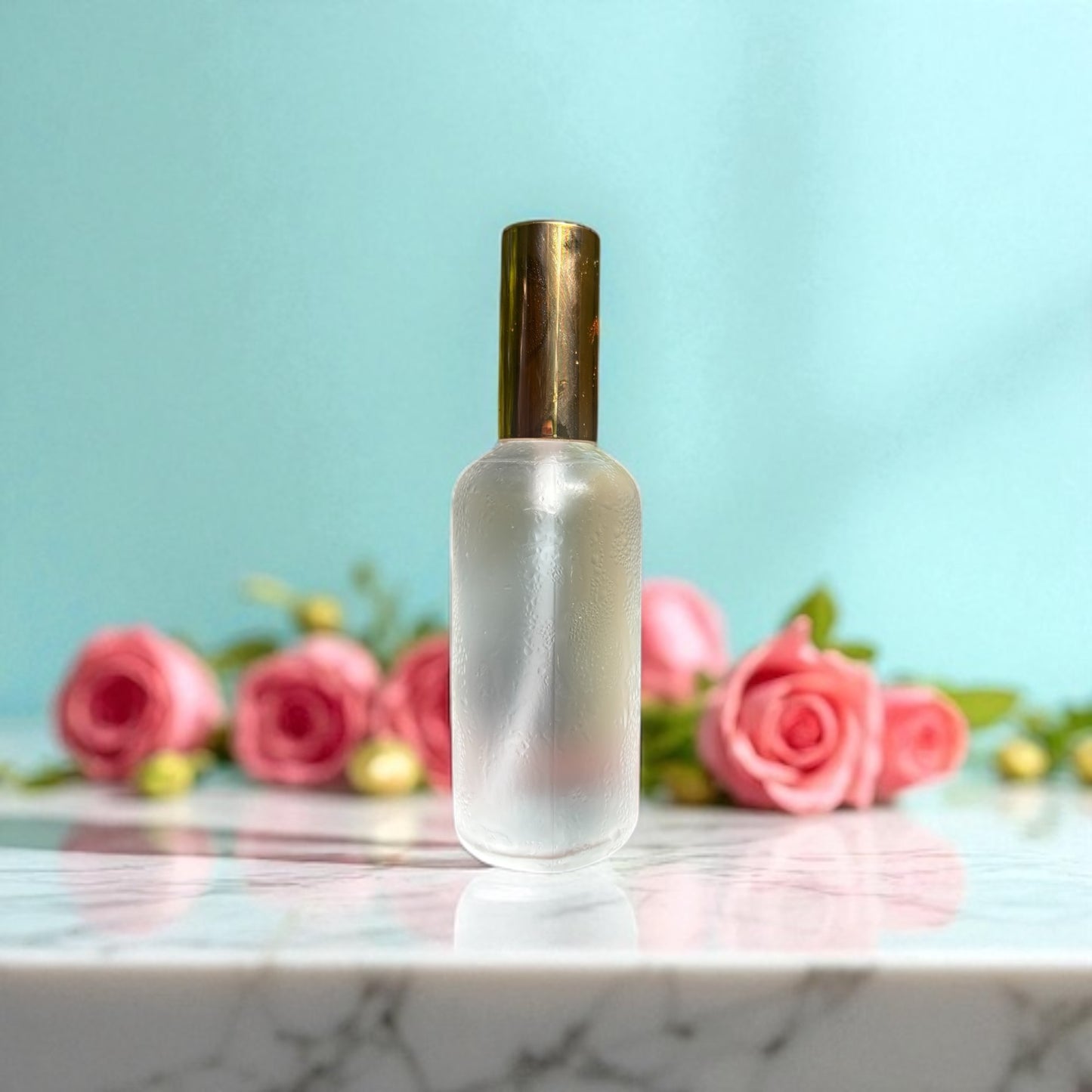 Frosted glass bottle with gold cap on a marble surface with pink roses in the background