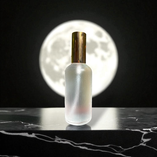 Frosted glass bottle with gold cap on a dark surface, moonlit background